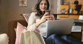 Femeie care face cumpărături online cu laptop și telefon, shopping digital, oferte speciale.